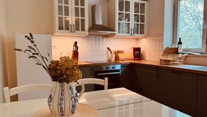 Cocina moderna con armarios blancos, una isla central y un ventanal con vistas a árboles.