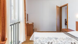 Una camera da letto con un letto, un comodino in legno, uno specchio e una finestra con tende.
