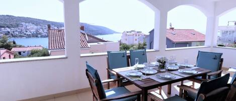A dining area with a table set for four, overlooking a scenic view of a coastal town.