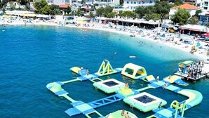 Vista aerea di una spiaggia con strutture gonfiabili per giochi acquatici e una zona di spiaggia sabbiosa.
