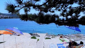Una spiaggia con ombrelloni, lettini e persone che si rilassano.
