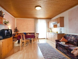 A cozy living room with wooden floors, a dining area with a table and chairs, a sofa, and a kitchen area with cabinets and a stove. - Hartlbauer in Dorfgastein by Interhome (Dorfgastein)