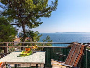 Ein Balkon mit Tisch, Stuhl und Blick aufs Meer.