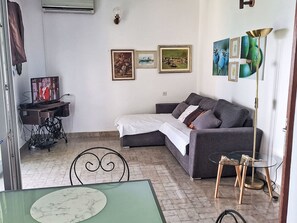 Un saló amb un sofà, una taula petita, una televisió i obra d'art a la paret.