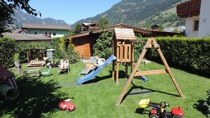 A backyard with a wooden playhouse, a slide, and a swing set. - in Dorfgastein by Interhome (Dorfgastein)
