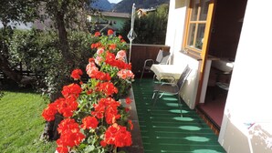 A garden with red flowers, a wooden fence, and a table with chairs. - in Dorfgastein by Interhome (Dorfgastein)