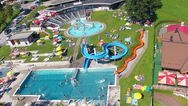 An aerial view of a water park with a large pool, a water slide, and sun loungers. - in Dorfgastein by Interhome (Dorfgastein)