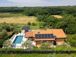Een huis met een zwembad, zonnepanelen en een tuin.