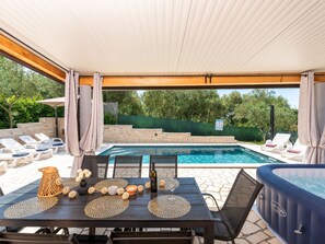 Een buitenzwembadgedeelte met ligbedden, een jacuzzi en een tafel gedekt met decoratieve objecten en een fles.