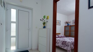 Quarto com cama, guarda-roupa e porta para outro cômodo.