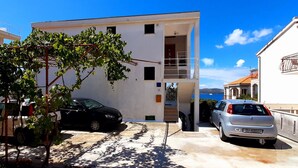 A modern two-story building with a white exterior, a visible staircase leading to the upper floor, and a car parked in the driveway. - Wohnung mit Blick auf das Wasser by Interhome (Trogir)