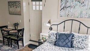 A bedroom with a bed, bedside table, lamp, and a painting on the wall.
