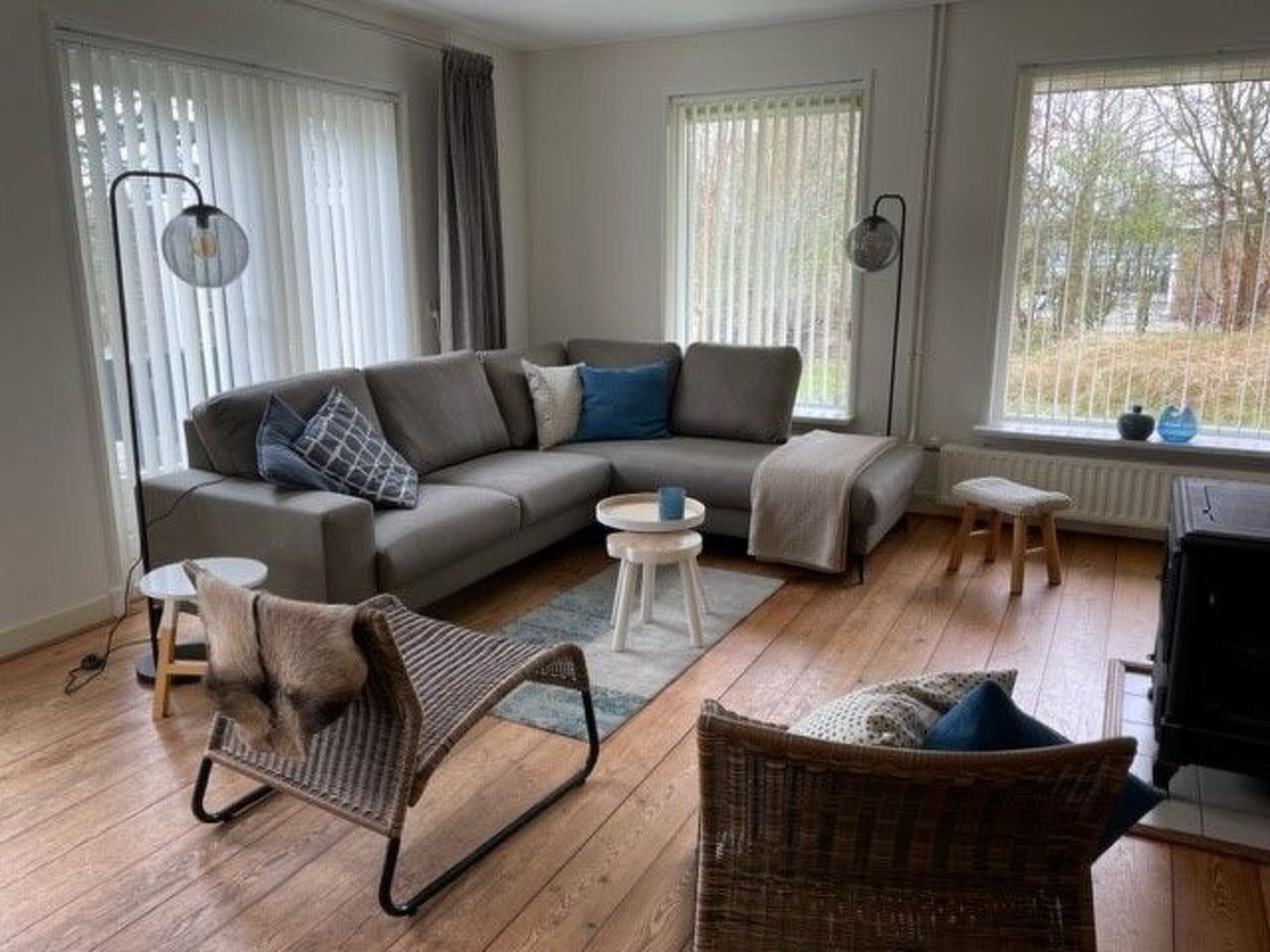 A modern living room with a sectional sofa, a wicker chair, a small table, and a fireplace.