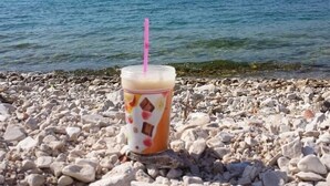 A plastic cup with a straw on a rocky beach with a view of a lake and hills in the background. - "MaLea" mit Blick auf das Wasser by Interhome (Trogir)
