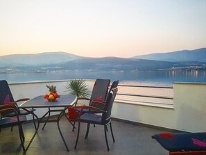 A terrace with a table and chairs, a fruit bowl, and a view of a body of water and distant mountains. - "MaLea" mit Blick auf das Wasser by Interhome (Trogir)