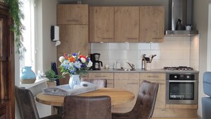 Une cuisine moderne avec des meubles en bois, un îlot central doté de chaises, une machine à café et un four.