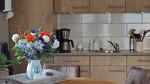 Une cuisine moderne avec des meubles en bois, un évier en acier inoxydable et une machine à café.