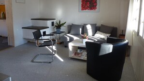 A modern living room with a sofa, coffee table, and a black chair. There is a plant on the coffee table, and a painting on the wall.