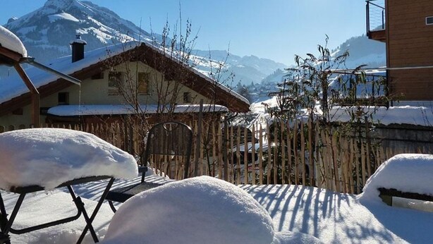A snow-covered mountain village with traditional wooden houses and a clear view of the mountain.
