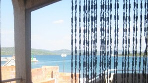 Un balcon avec vue sur la mer, un sol en pierre et un rideau suspendu.
