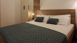 Une chambre à coucher avec un lit, une table de chevet, une lampe et une armoire.
