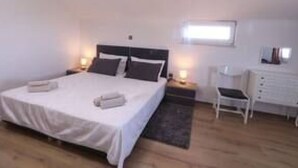 Un dormitorio con cama, mesitas de noche, una silla y un aparador.