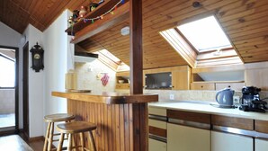 A kitchen with wooden cabinets, a bar counter, stools, and a skylight. - Ruhige Ferienwohnung mit herrlicher Aussicht by Interhome (Dragovode)
