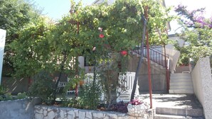 Un muro de piedra con un jardín, una escalera y un edificio al fondo.