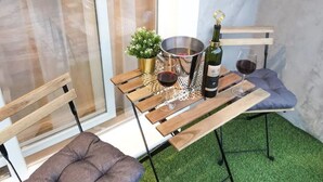 A small patio area with a wooden table, two cushioned chairs, a small potted plant, a metal bowl, and a bottle of wine. - Apartment Neda by Interhome (Vinišće)