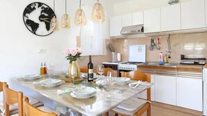 A modern kitchen with white cabinets, a gas stove, and hanging pendant lights. - Apartment Neda by Interhome (Vinišće)