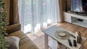 A living room with a sofa, a coffee table, a TV, and a stone wall. - Apartment Neda by Interhome (Vinišće)