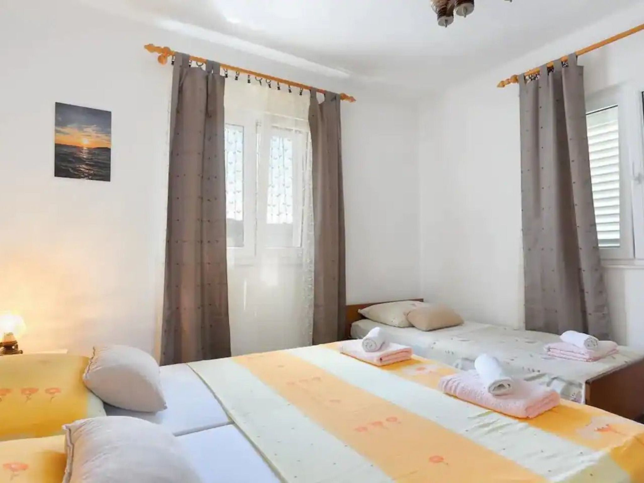 Hotelkamer met twee bedden, een raam met gordijnen, een schilderij aan de muur en een nachtkastje met handdoeken.