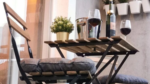 A small outdoor seating area with a table and chairs, a potted plant, and a wine bottle. - Apartment Neda by Interhome (Vinišće)