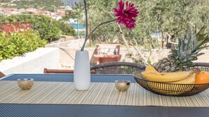 A table with a white vase, a pink flower, a pineapple, bananas, and an orange on a woven mat. - Modernes Ferienhaus mit Terrasse und Meerblick by Interhome (Vinišće)