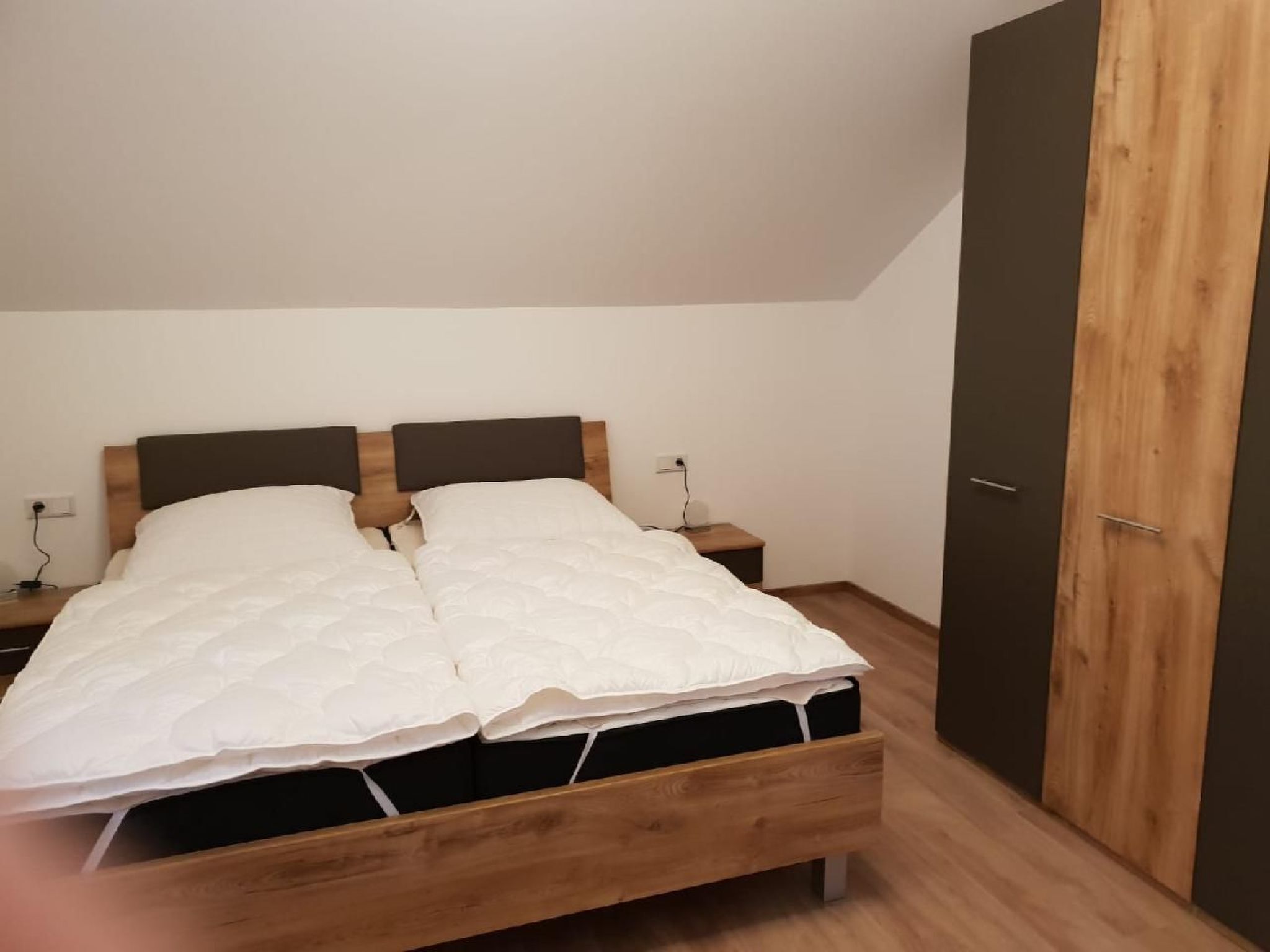 Une chambre à coucher avec un lit en bois, une table de chevet et une armoire.