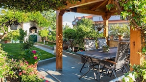 Un espace extérieur aménagé en terrasse, avec une pergola, des sièges et des plantes en pot.