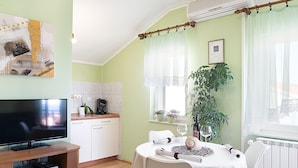 Un salon confortable avec un téléviseur, une table à manger avec des chaises, une machine à café et une plante en pot.