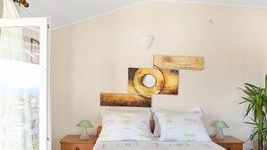 Une chambre à coucher avec un lit, deux tables de chevet, une lampe fixée au mur et une plante en pot.