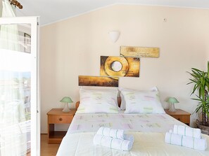A bedroom with a bed, two nightstands, a wall-mounted lamp, and a potted plant. - Appartement mit Balkon by Interhome (Šibenik)