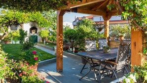 Un espace extérieur aménagé en terrasse, avec une pergola, des sièges et des plantes en pot.