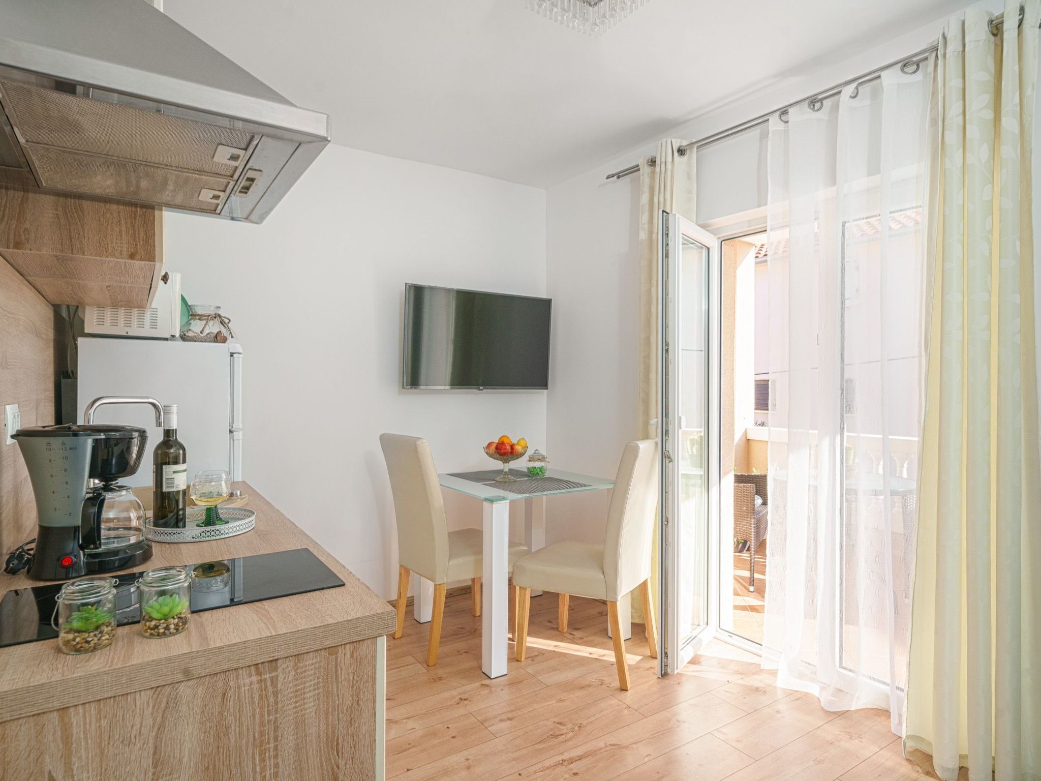 A modern kitchen with a coffee maker, a TV, and a dining area with a table and chairs.