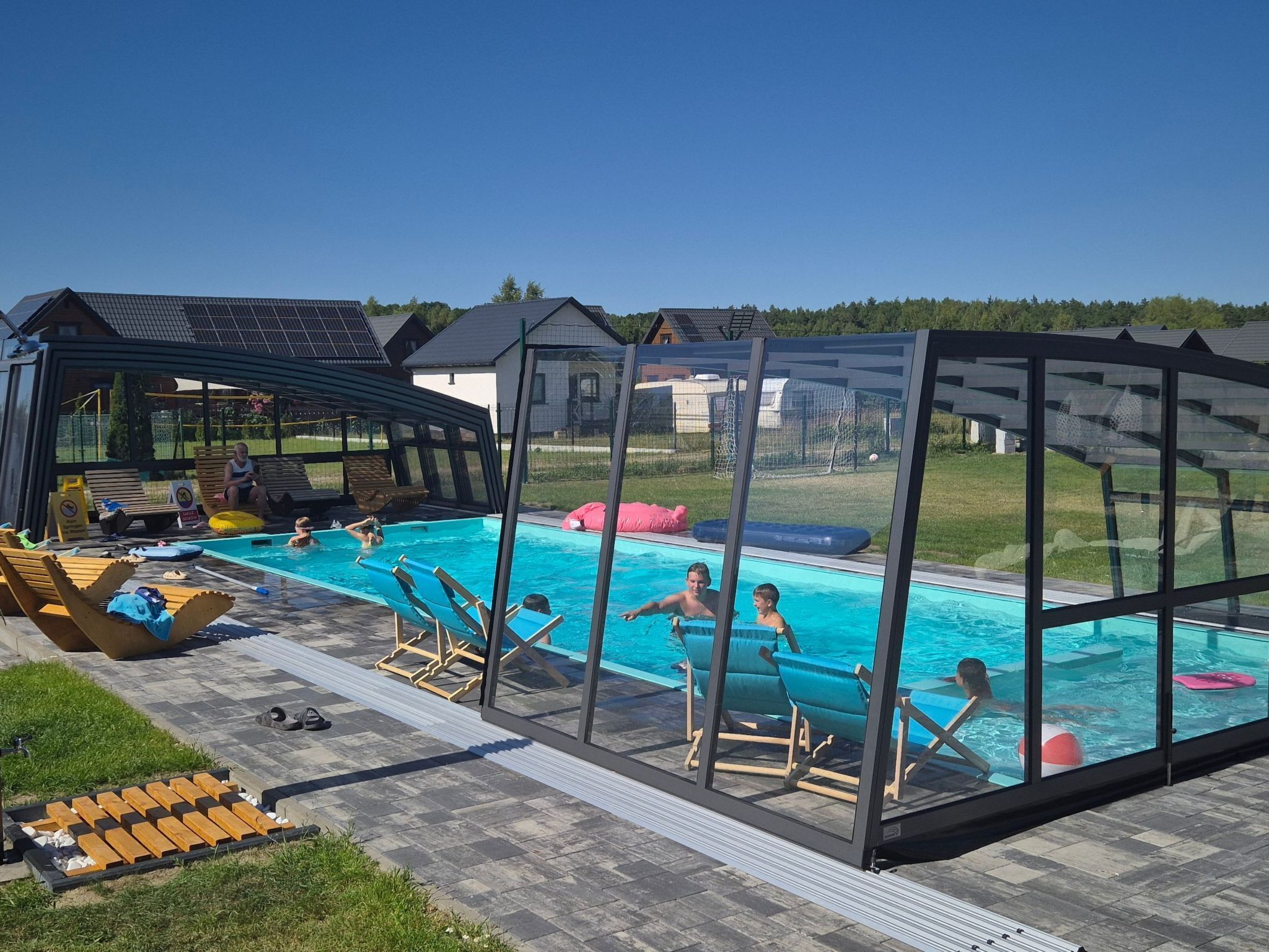 Une piscine entourée de parois en verre, des chaises longues et un espace salon abrité.