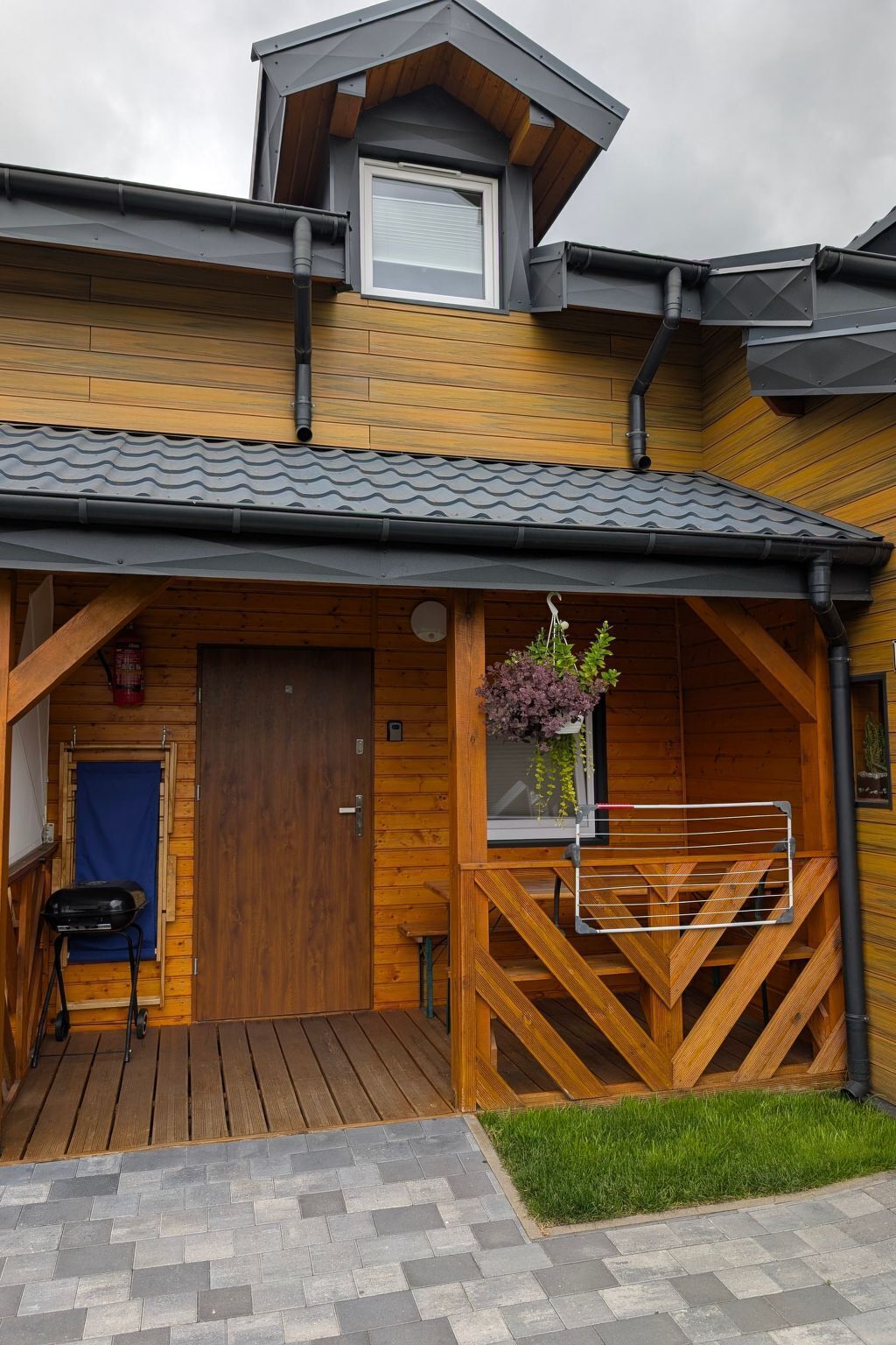 A wooden cabin with a sloped roof, a covered porch, and a small outdoor seating area.