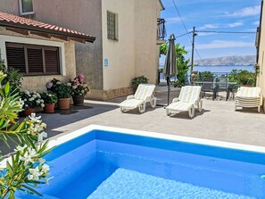 A swimming pool with lounge chairs, potted plants, and a view of the sea. - Gesamte Wohnung mit Terrasse und Meerblick by Interhome (Senj)