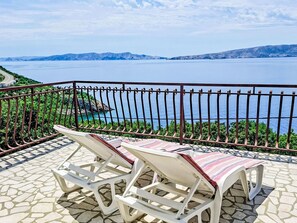 A balcony with two white lounge chairs and a patterned table, overlooking a scenic view of a body of water and distant mountains. - Gesamte Wohnung mit Terrasse und Meerblick by Interhome (Senj)
