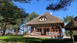 Ein traditionelles Haus mit einem Reetdach, einer Holzveranda und weißen Gittergeländern.