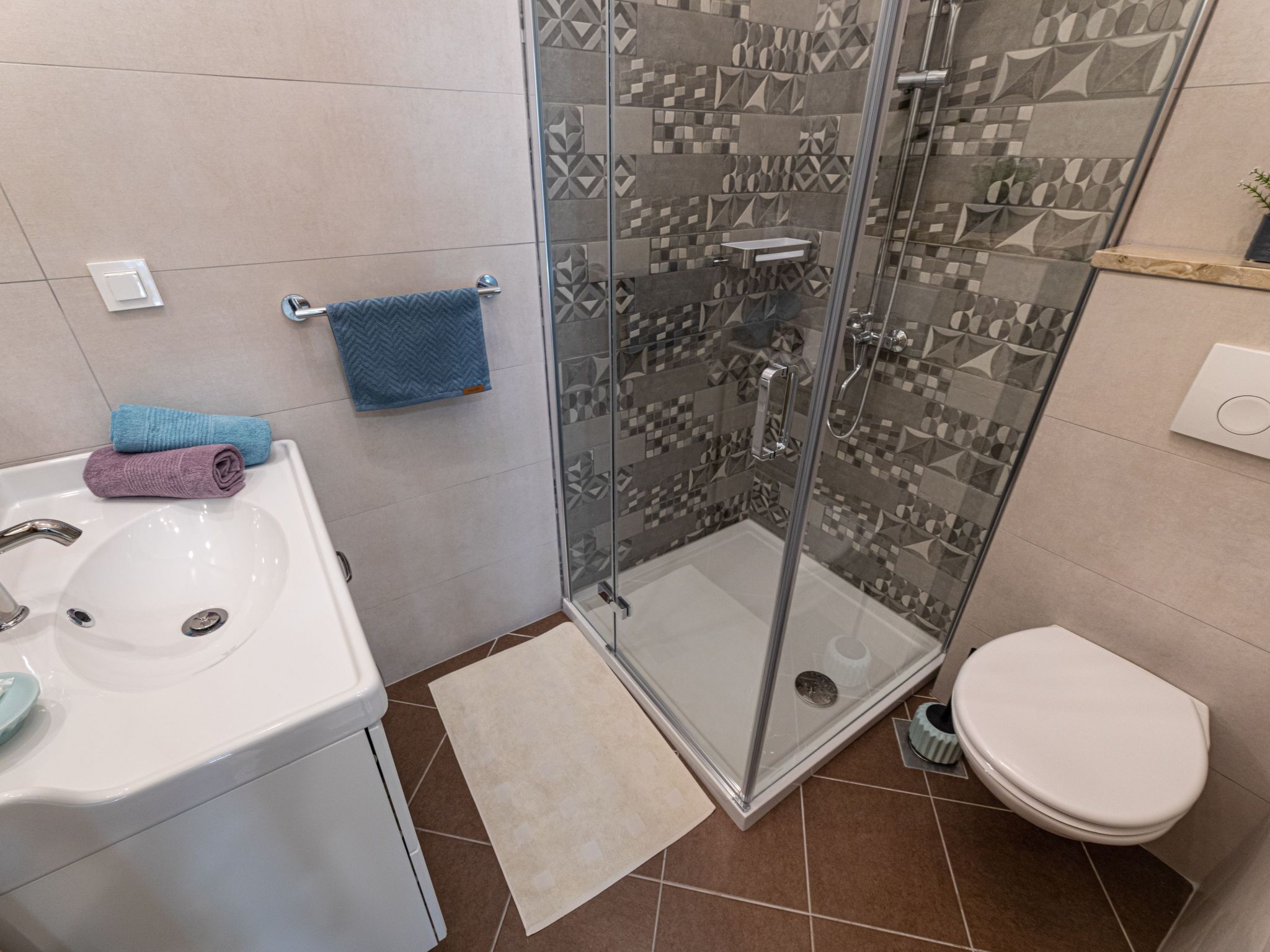 Un bany amb plat de dutxa de vidre, un lavabo i un vàter.