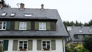 A two-story house with green shutters, a stone foundation, and a sloped roof with skylights. - am Wald mit Sauna by Interhome (Bad Elster)