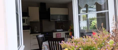 A kitchen with cabinets, a microwave, and a window with curtains.