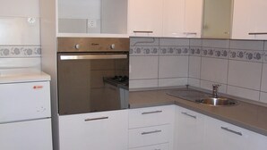 A compact kitchen with white cabinets, a built-in stove, and a sink. - Zwei-Zimmer-Wohnung Radosav by Interhome (Krk/Šilo)